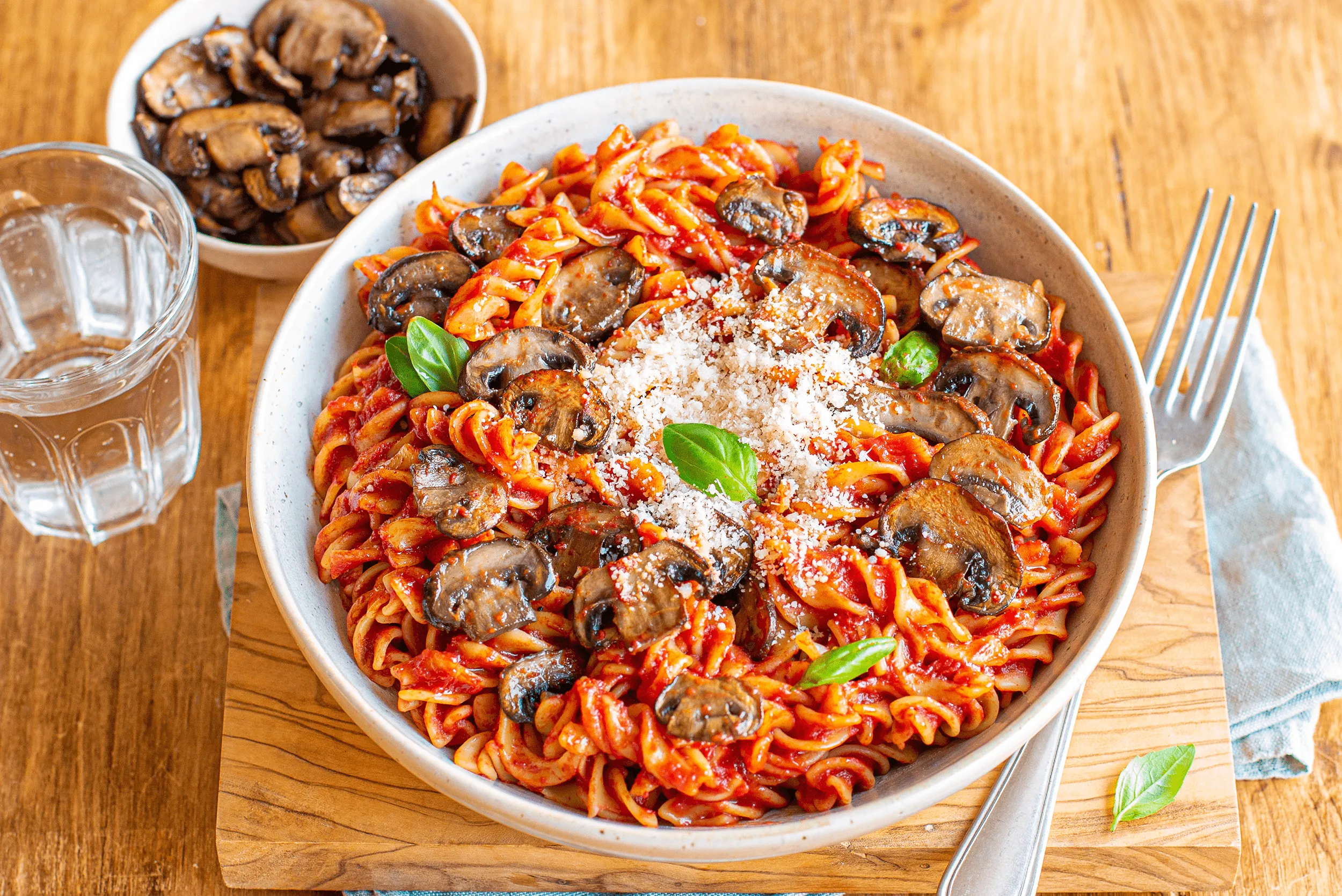 Plat de fusilli Panzani au Tomacouli, champignons frais et copeaux de parmesan, saveurs méditerranéennes.