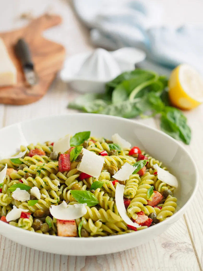 Saladier de fusilli verts au pesto, tomates cerises, câpres, copeaux de parmesan et basilic.