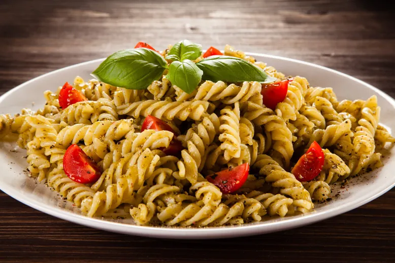 Assiette de fusilli au pesto, tomates cerises et basilic frais.