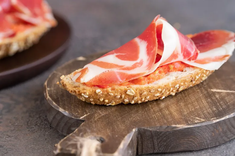 Tartine de pain aux céréales avec sauce tomate et jambon cru.