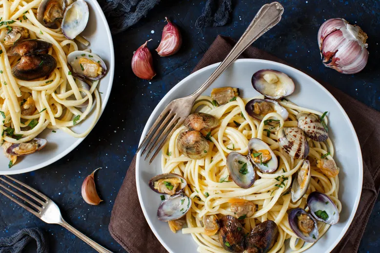 Deux assiettes de spaghetti alle vongole (palourdes) avec ail frais.