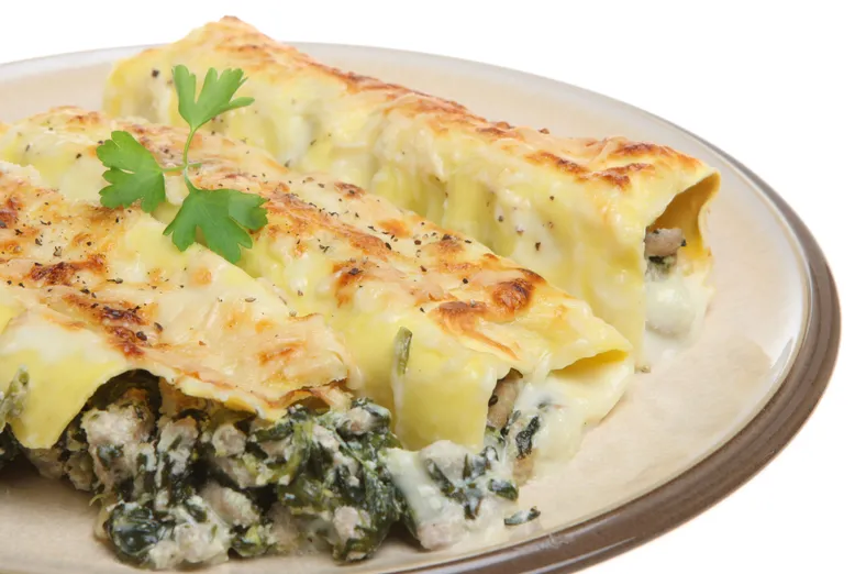Deux cannellonis gratinés aux épinards, viande hachée et béchamel, sur une assiette.