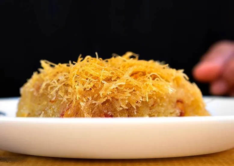 Gros plan sur un dessert oriental (kadaif) avec une garniture de vermicelles dorés.