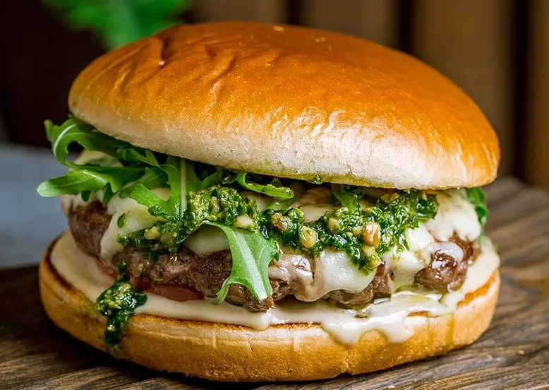 Burger gastronomique avec steak épais, fromage fondu, pesto et roquette.