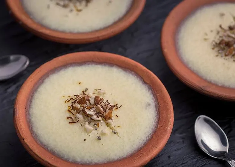 Trois bols en terre cuite de riz au lait garnis d'amandes effilées et safran.