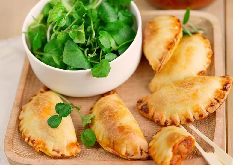 Petits chaussons salés (empanadas) avec une salade de cresson en accompagnement.