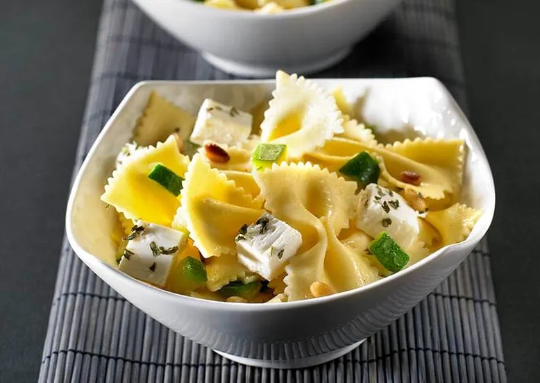 Bol de salade de farfalle à la feta, courgettes et pignons de pin.