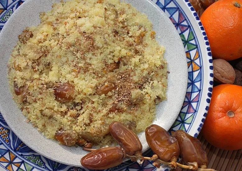 Assiette de couscous aux dattes, graines de sésame et noix, avec des oranges.