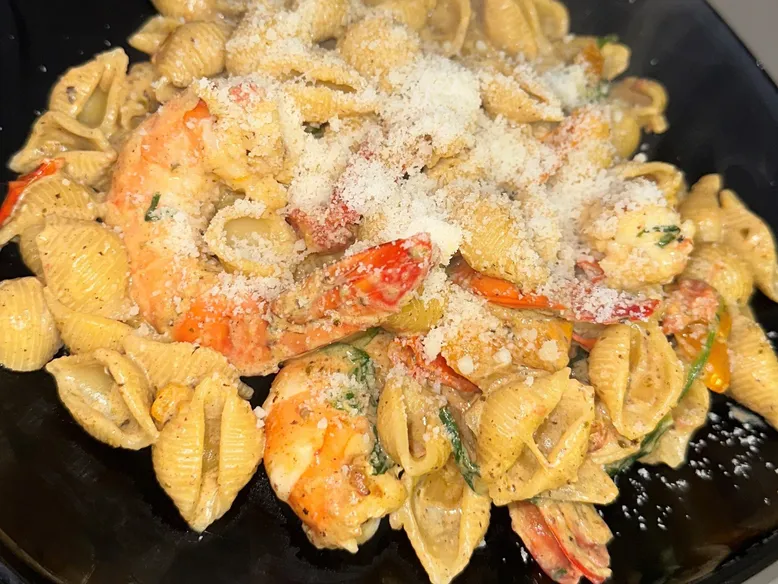Assiette de conchiglie aux crevettes, poivrons et parmesan râpé.